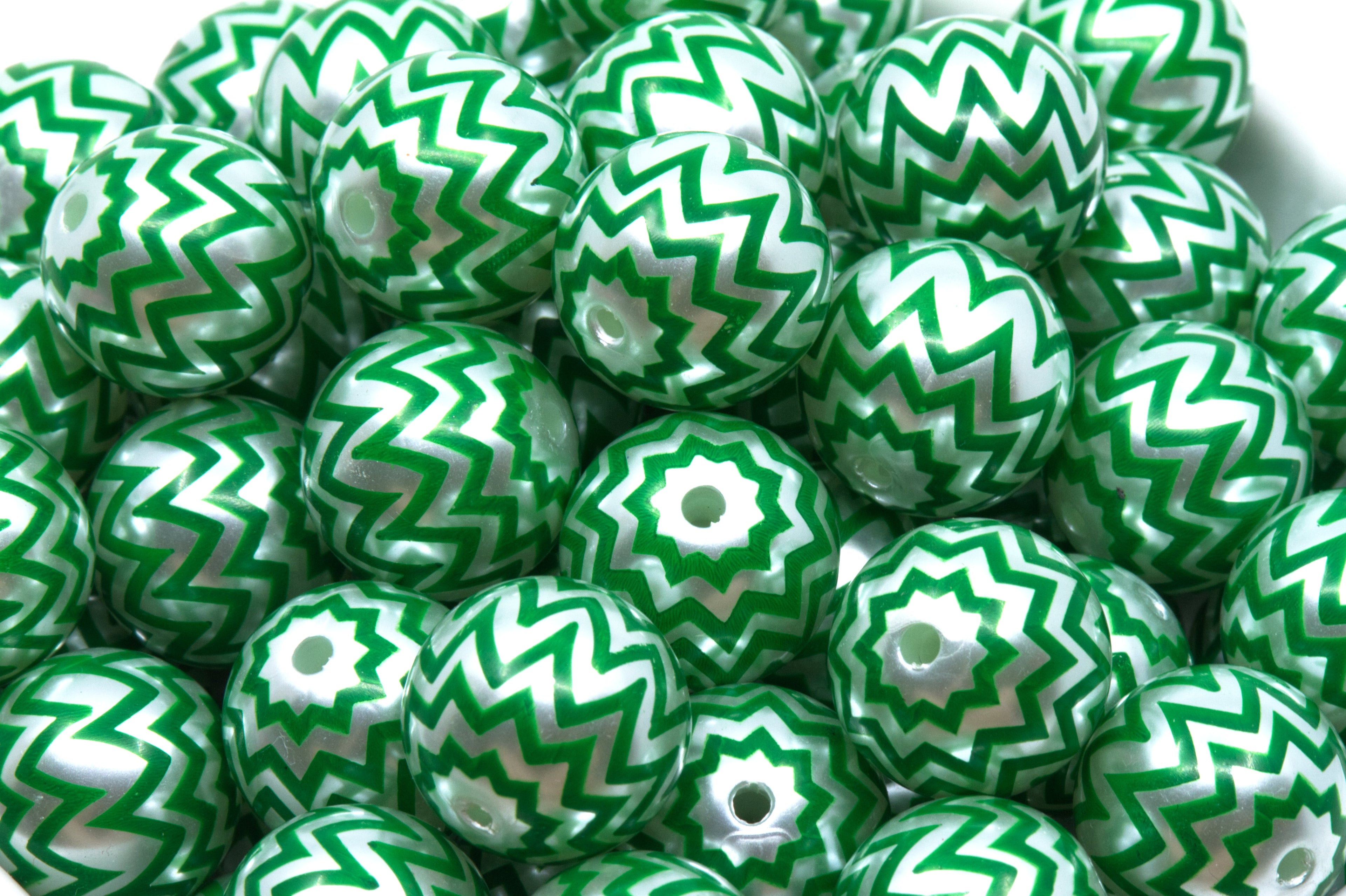 A close-up of many green and silver chevron-patterned round beads filling the frame.