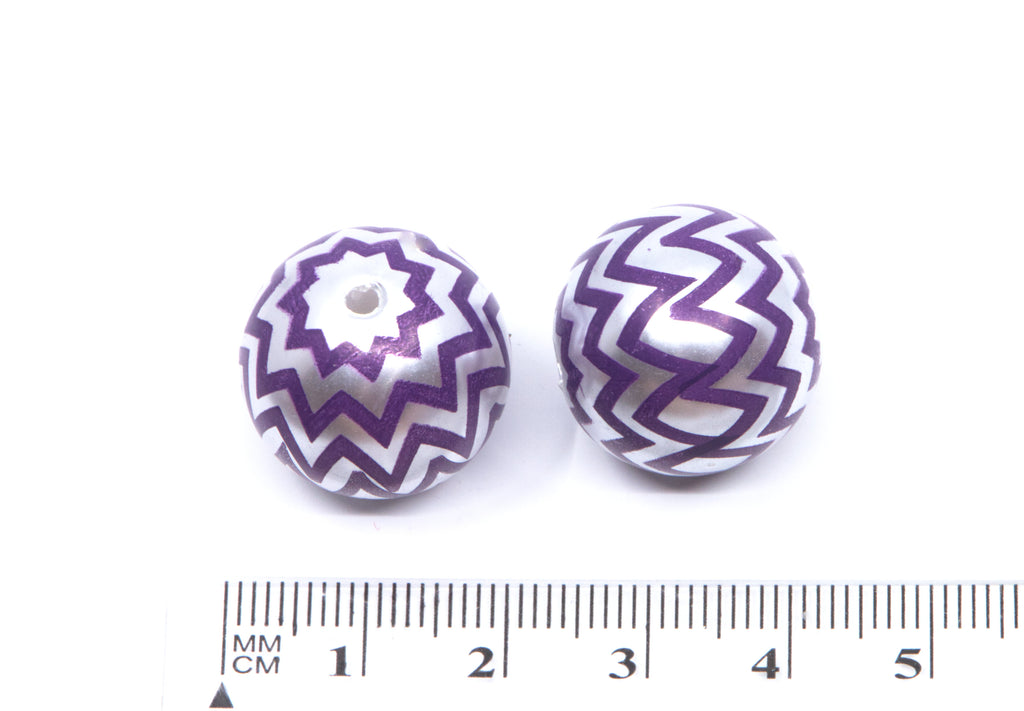 Two round silver beads with a purple chevron pattern, shown next to a cm ruler for scale on a white background.