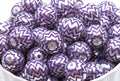 A pile of round craft beads with a purple and silver chevron pattern, shown in a white container.