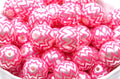 A pile of  pink and silver chevron-patterned round beads in a white container. 