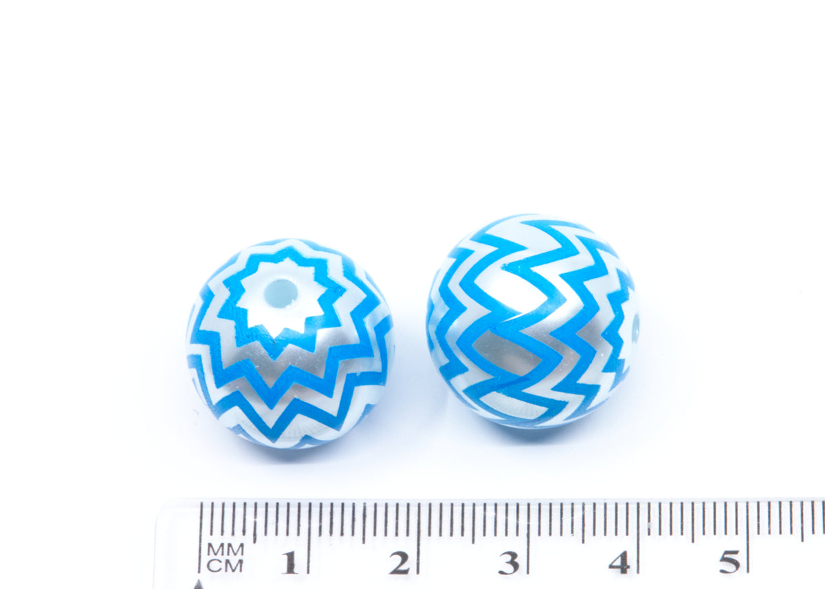 Two round glass acrylic with blue and silver chevron patterns, shown next to a cm ruler for scale on a white background.