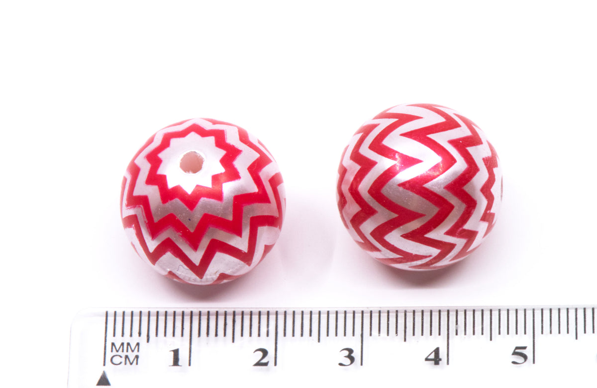 Two round red and silver patterned beads shown next to a cm ruler for scale on a white background.