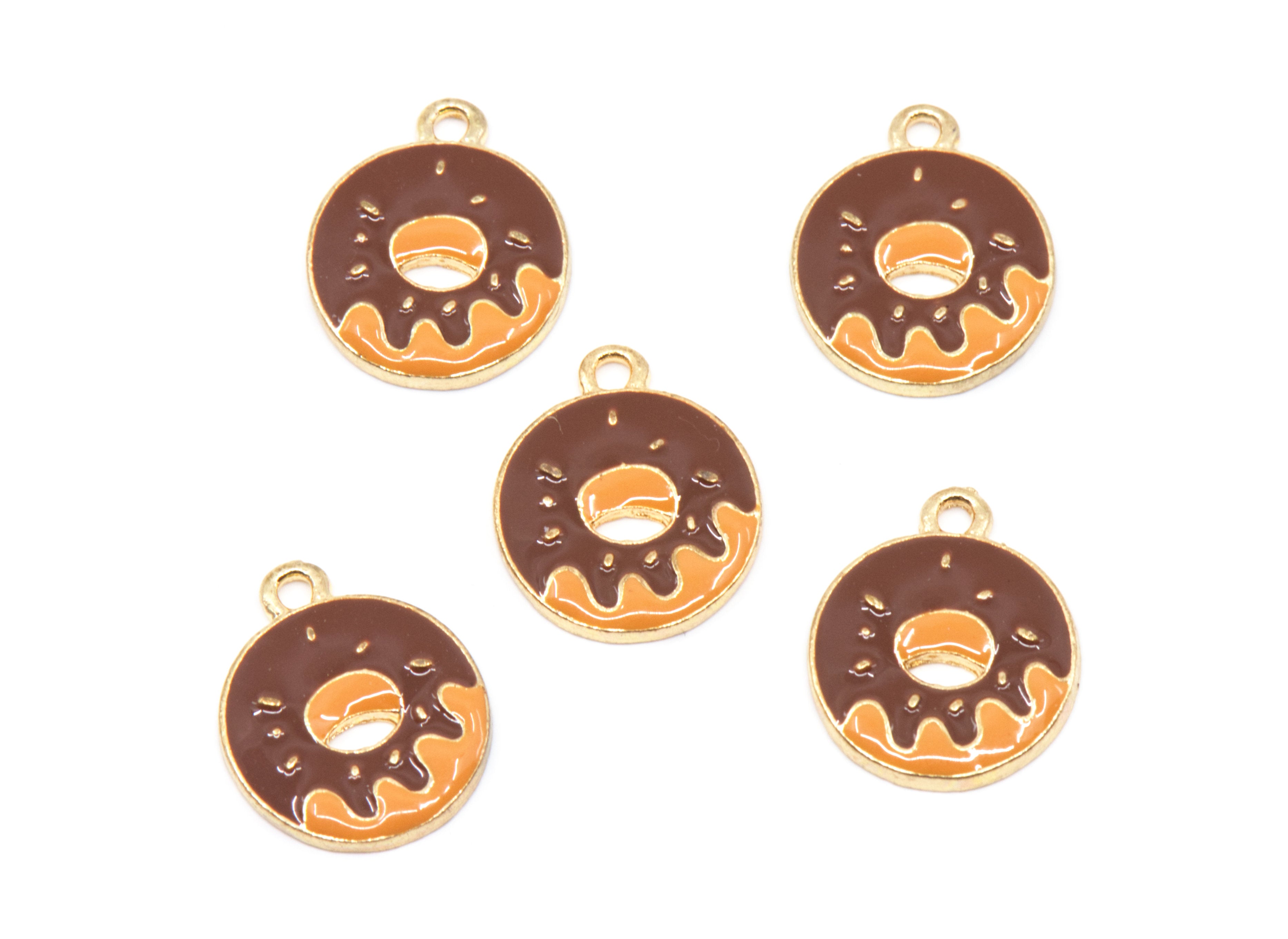 Five donut-shaped jewelry charms with gold-tone edges, featuring a dark brown chocolate-glazed design with orange icing details, arranged on a plain white background.