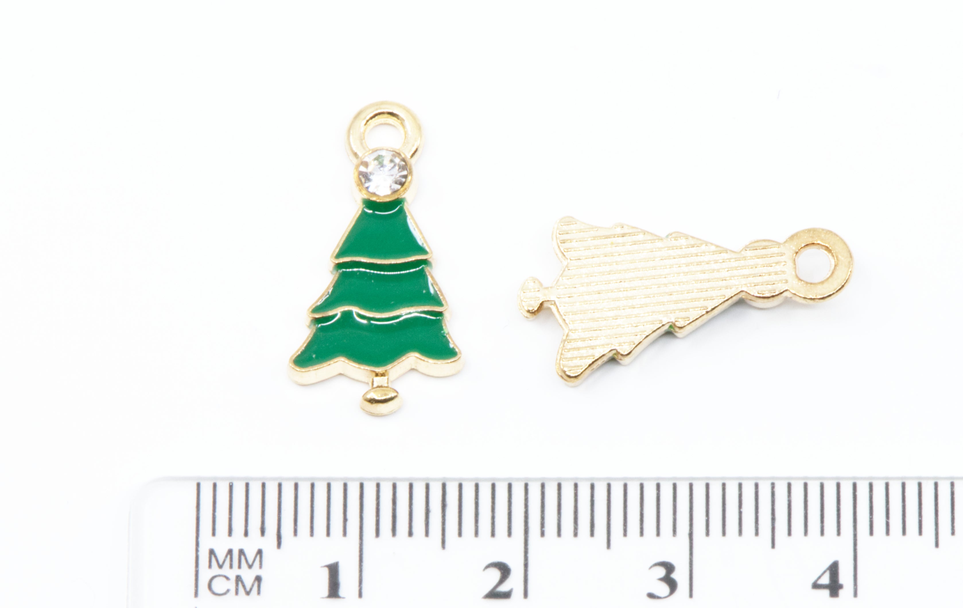 Two small gold-tone Christmas tree charms shown next to a cm ruler for scale on a white background.