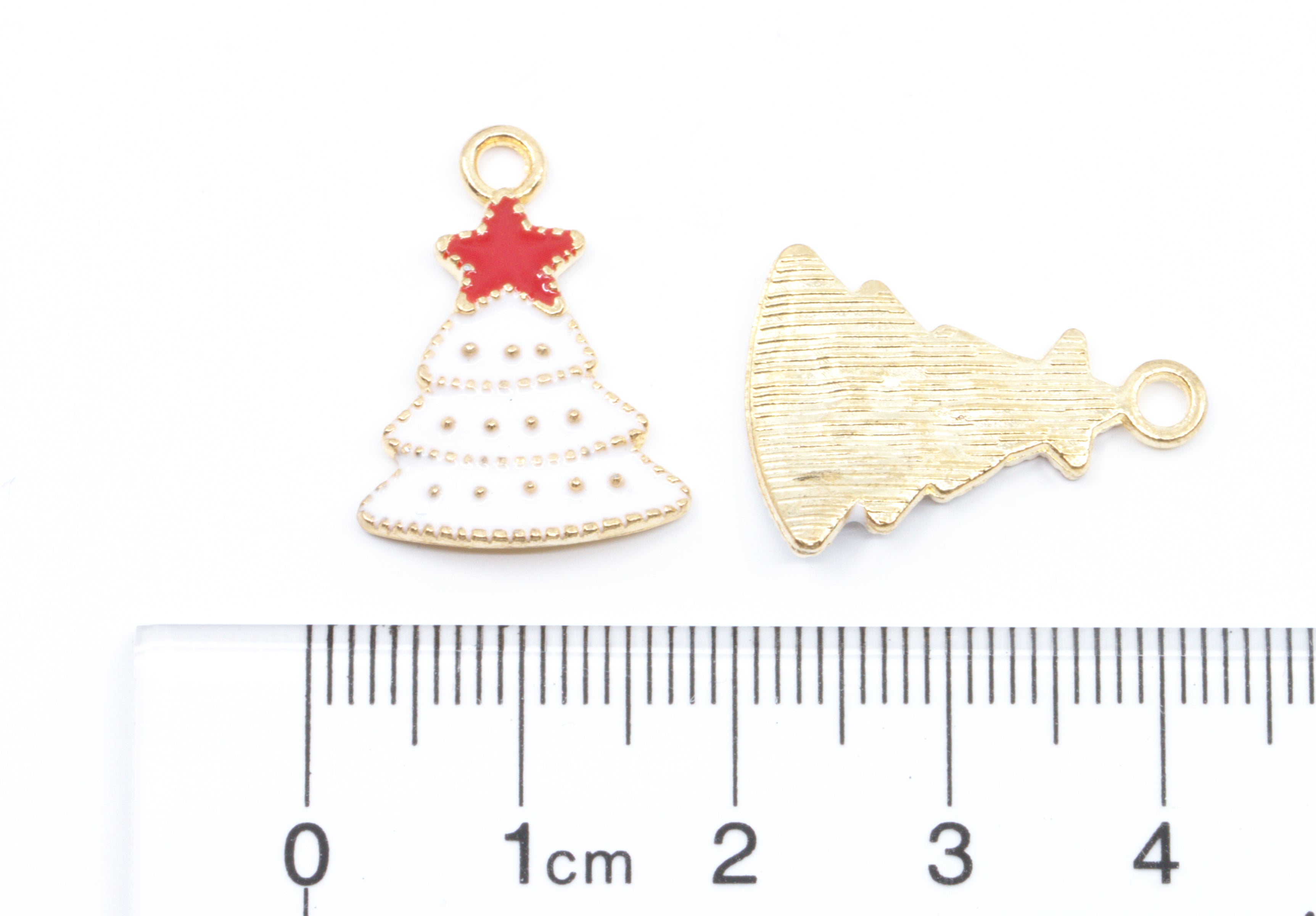 Two white Christmas tree with red star charms on a white background with a cm ruler at the bottom for scale. 