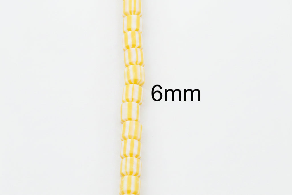 A single strand of small yellow and white striped polymer clay barrel beads shown vertically on a plain white background, with the text '6mm' indicating the bead size. 