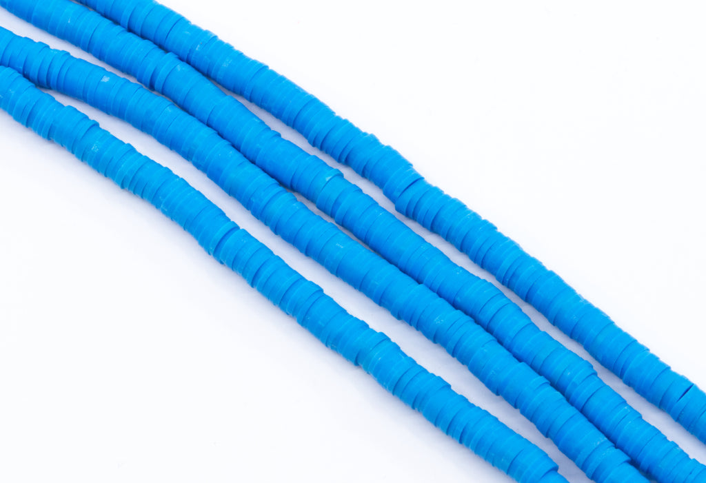 multiple strands of blue polymer clay disc beads arranged in diagonal rows on a clean white background.