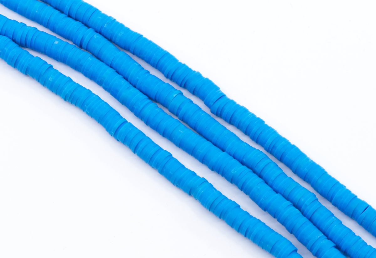 multiple strands of blue polymer clay disc beads arranged in diagonal rows on a clean white background.