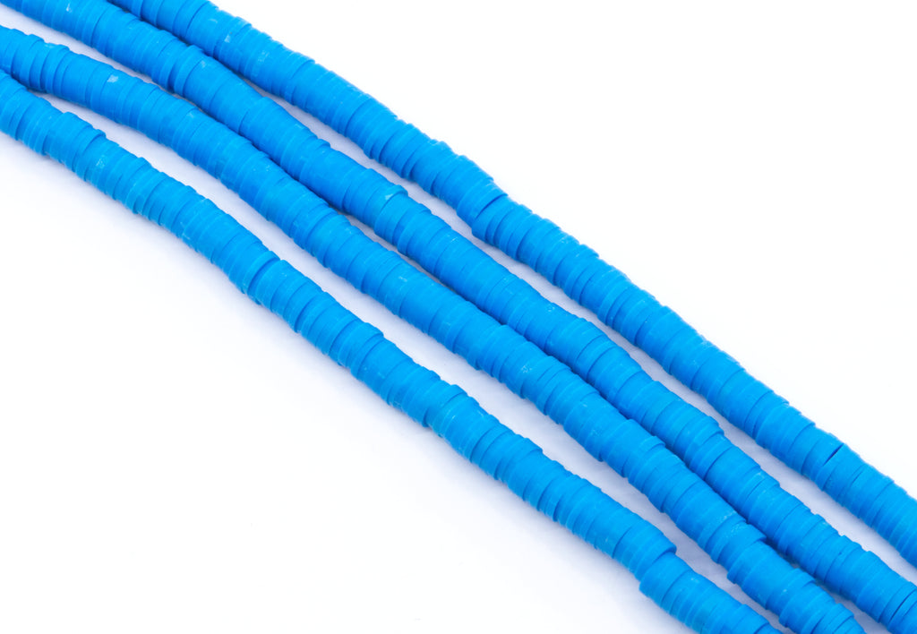 multiple strands of blue polymer clay disc beads arranged in diagonal rows on a clean white background.