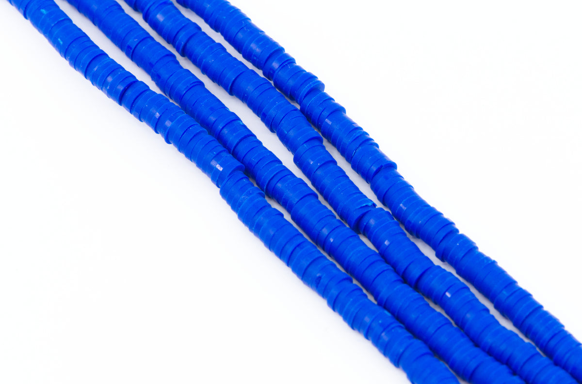 multiples strand of blue polymer clay disc beads arranged diagonally on a plain white background.