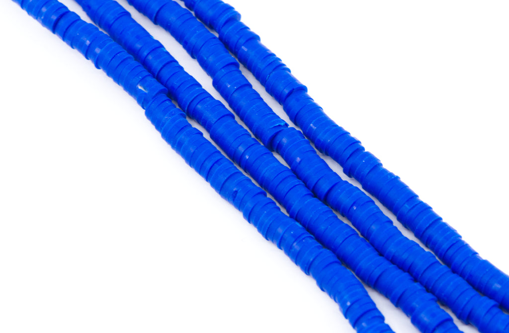 multiples strand of blue polymer clay disc beads arranged diagonally on a plain white background.