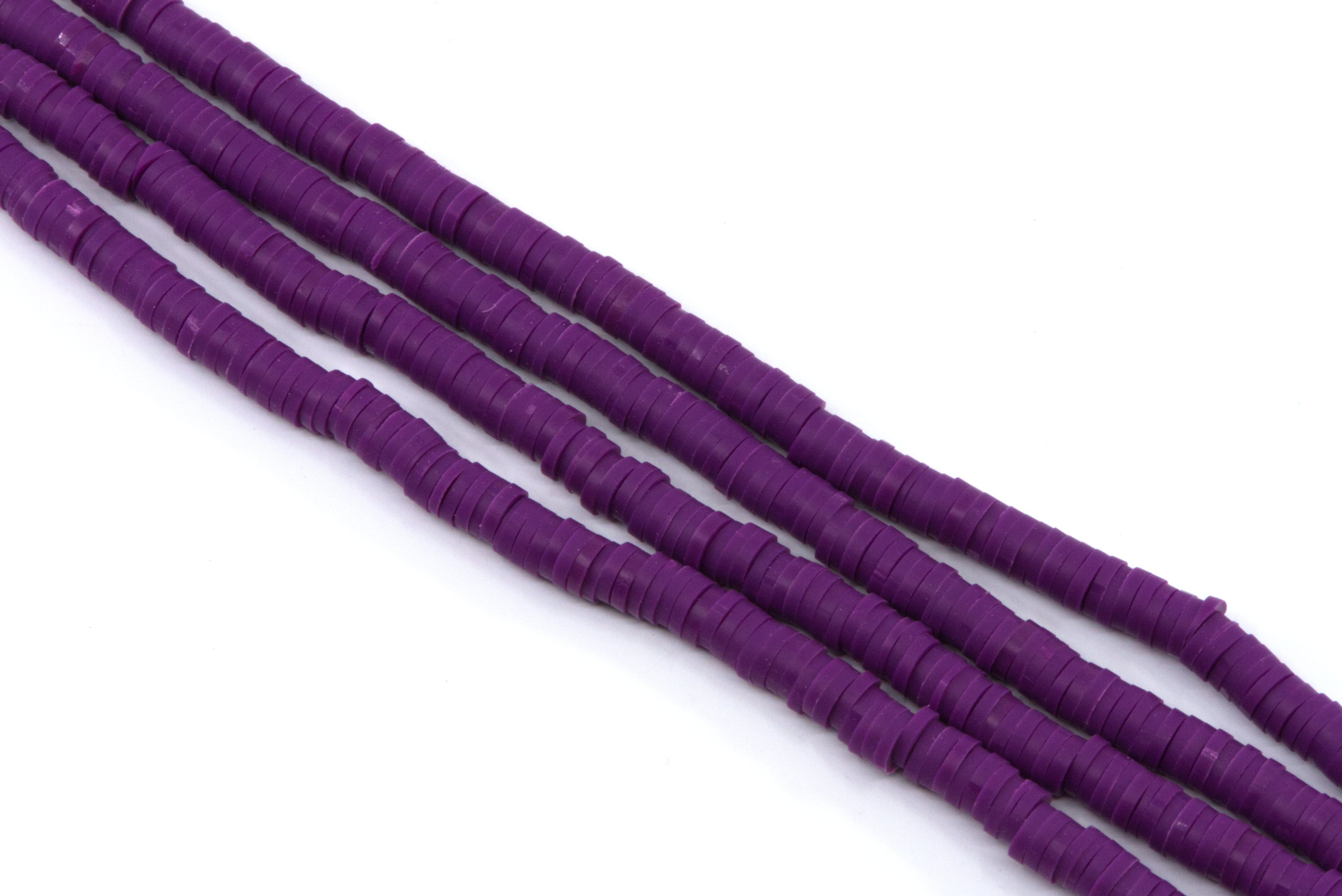 multiple strands of purple polymer clay disc beads arranged diagonally on a plain white background.
