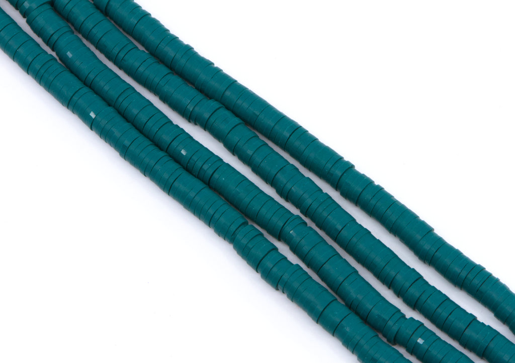 multiple strands of teal polymer clay disc beads  arranged diagonally on a plain white background.