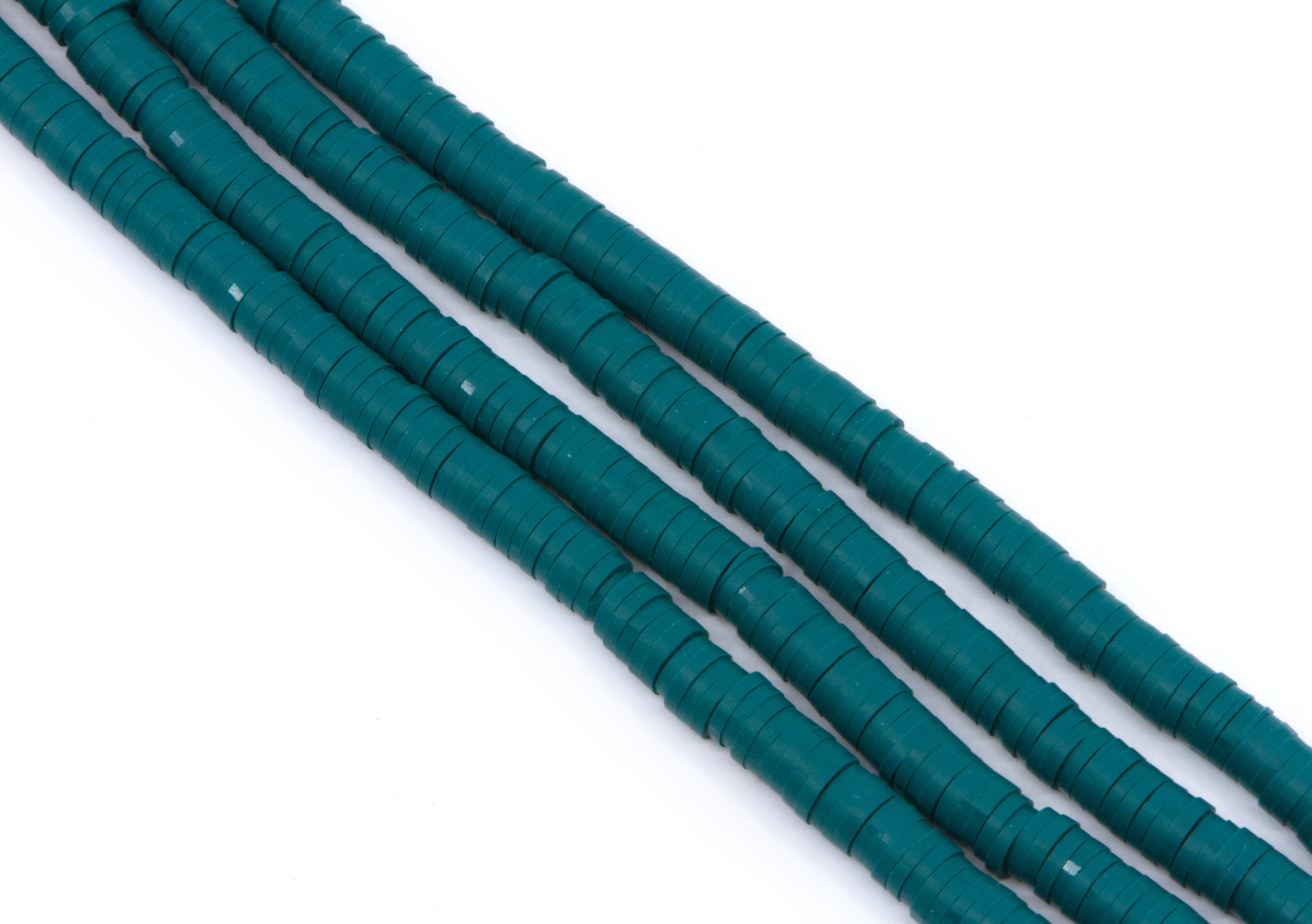 multiple strands of teal polymer clay disc beads  arranged diagonally on a plain white background.