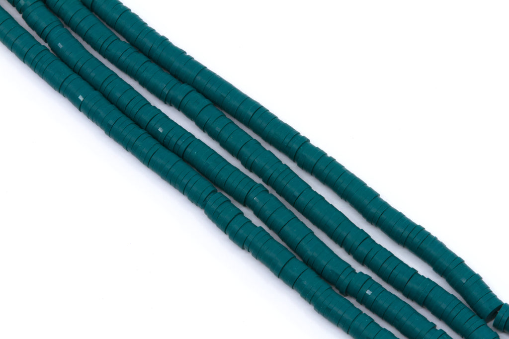 multiple strands of teal polymer clay disc beads  arranged diagonally on a plain white background.