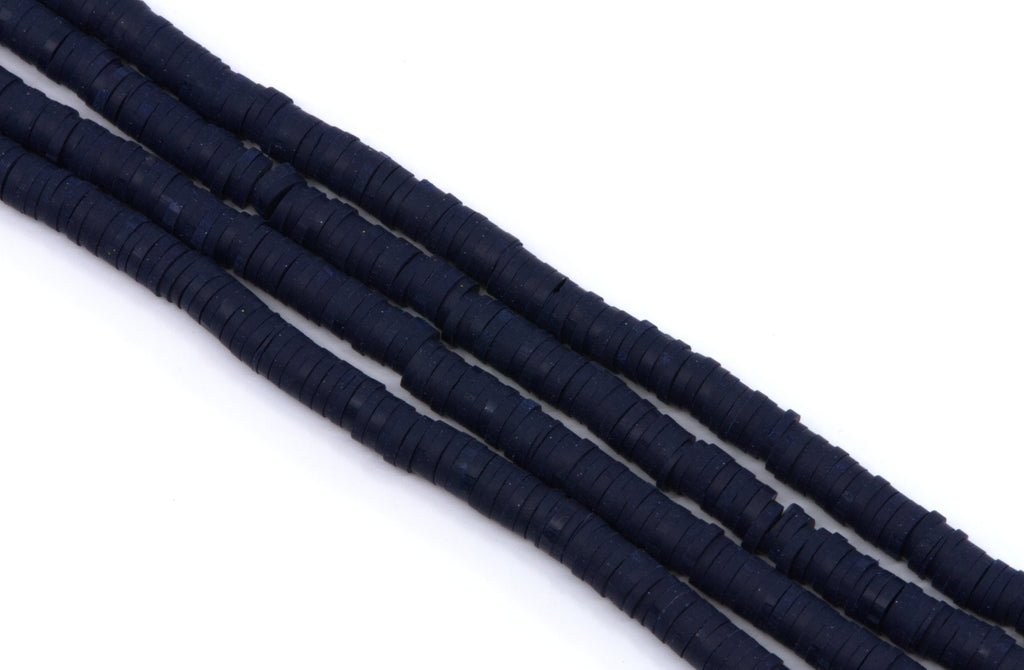multiple strands of navy blue polymer clay beads, arranged diagonally on a plain white background.