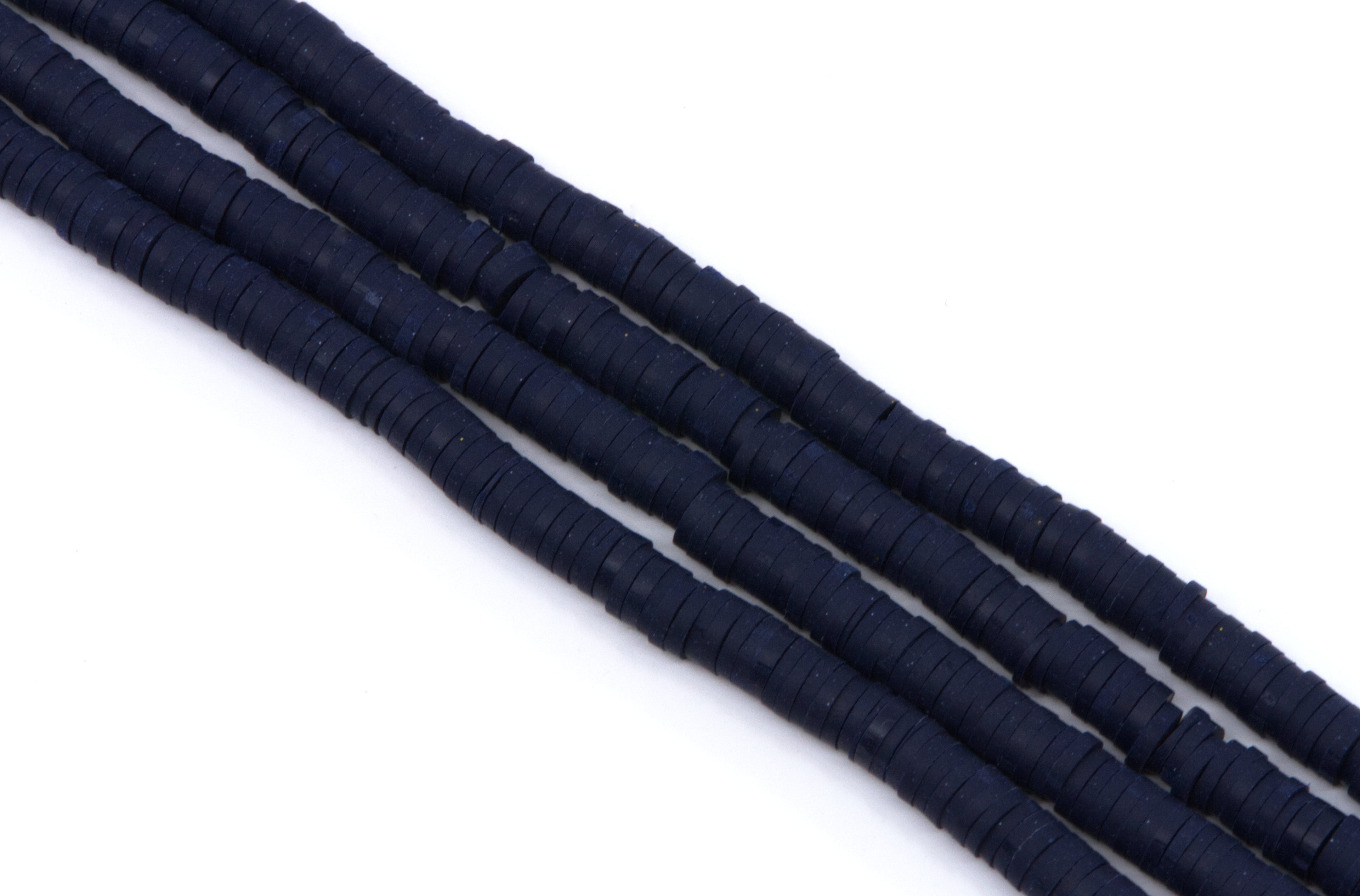 multiple strands of navy blue polymer clay beads, arranged diagonally on a plain white background.