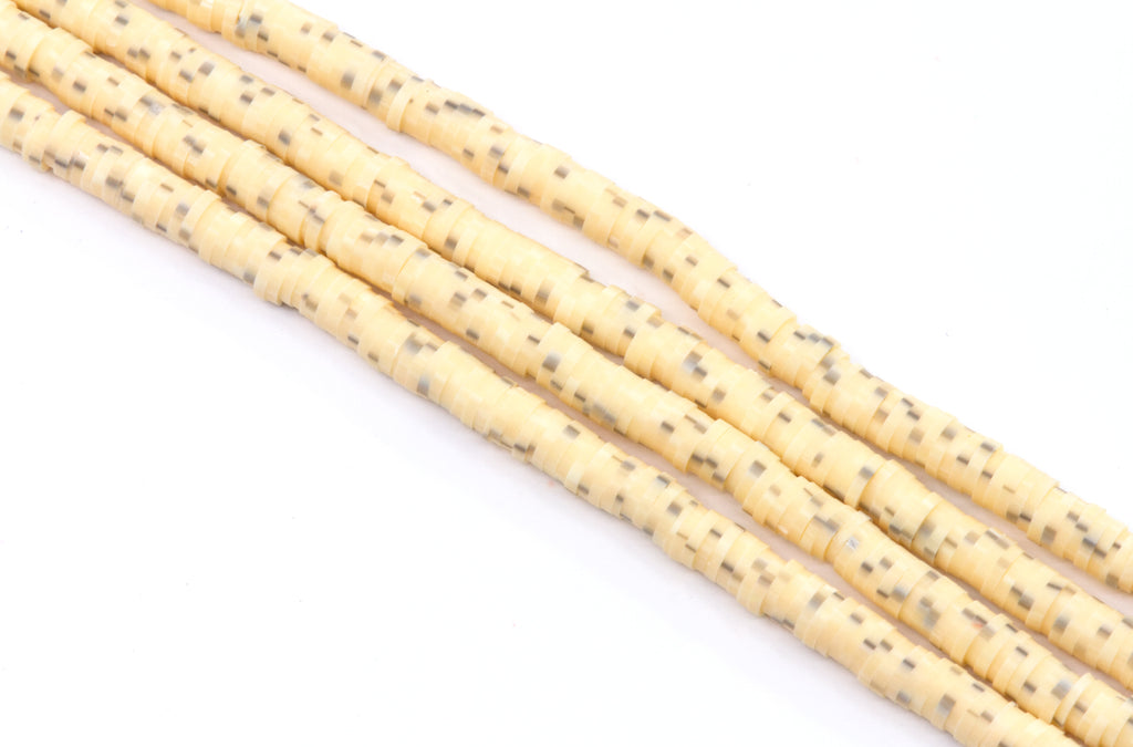 multiple strands of light orange polymer clay disc beads  arranged diagonally on a white background.