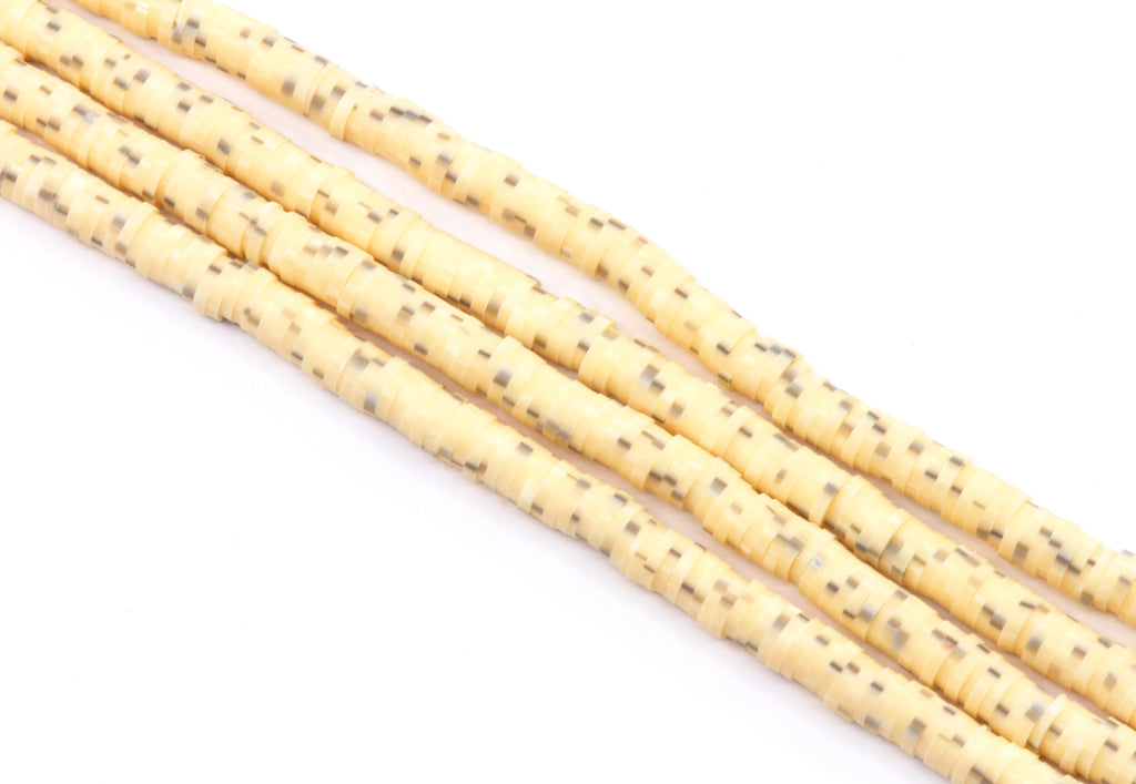 multiple strands of light orange polymer clay disc beads  arranged diagonally on a white background.
