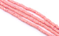 multiple strand of pink polymer clay beads arranged diagonally on a white background.