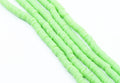 multiple strands of light green polymer clay disc beads  photographed diagonally on a clean white background.