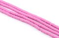 multiple strands of pink polymer clay disc beads arranged diagonally on a clean white background.