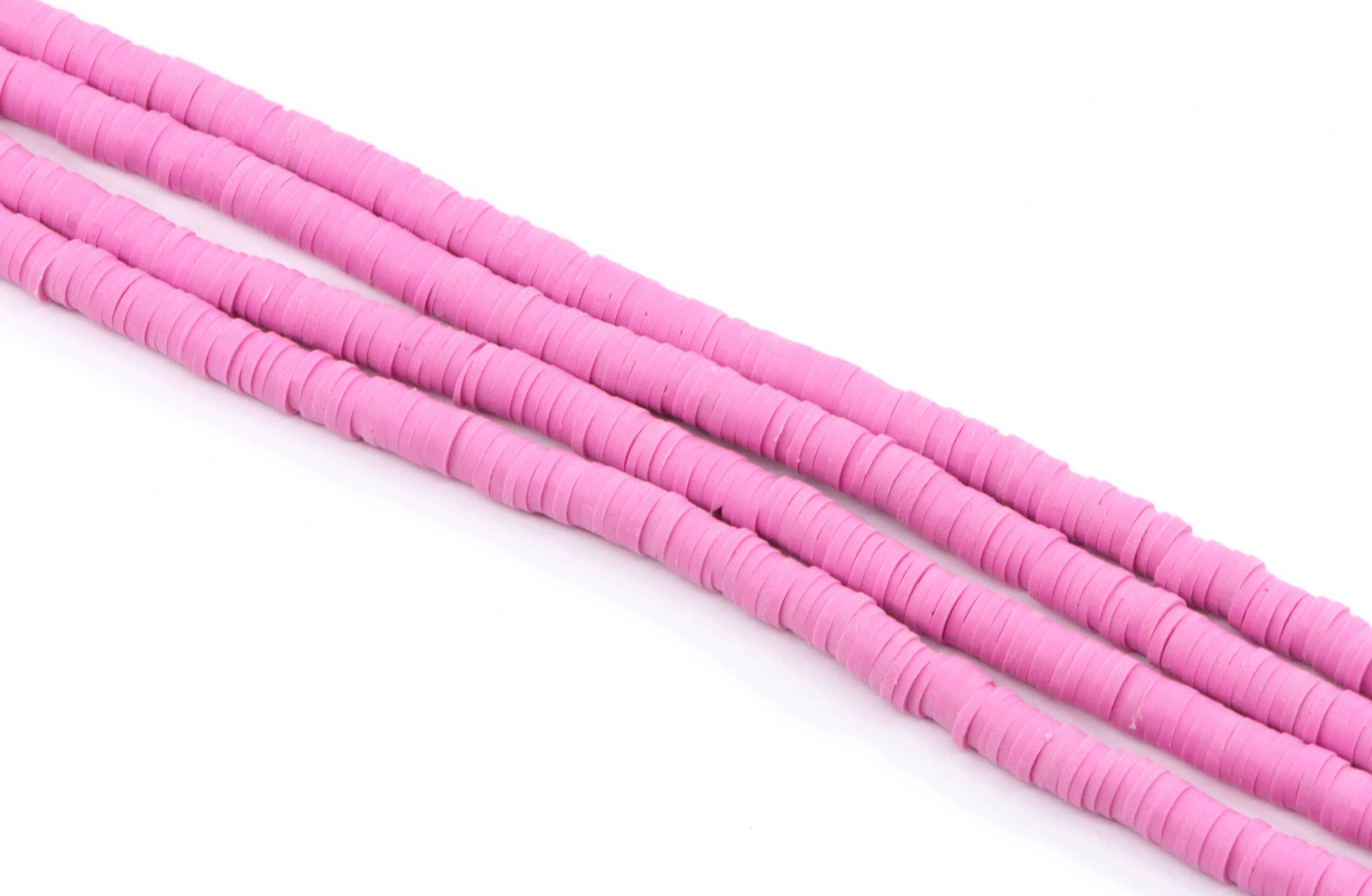 multiple strands of pink polymer clay disc beads arranged diagonally on a clean white background.