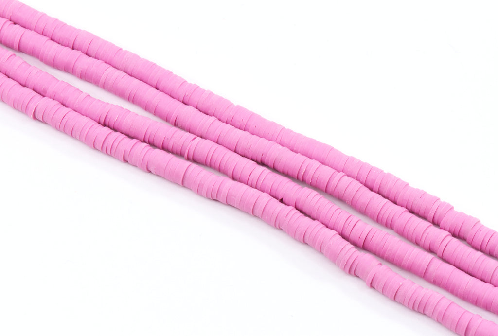 multiple strands of pink polymer clay disc beads arranged diagonally on a clean white background.