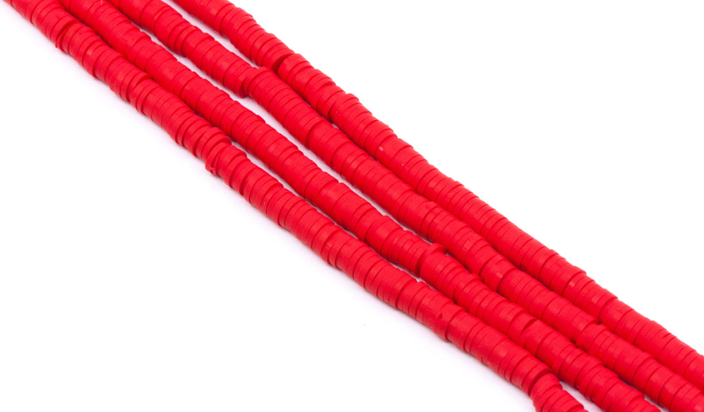 Several strands of red polymer clay disc beads arranged diagonally on a plain white background.