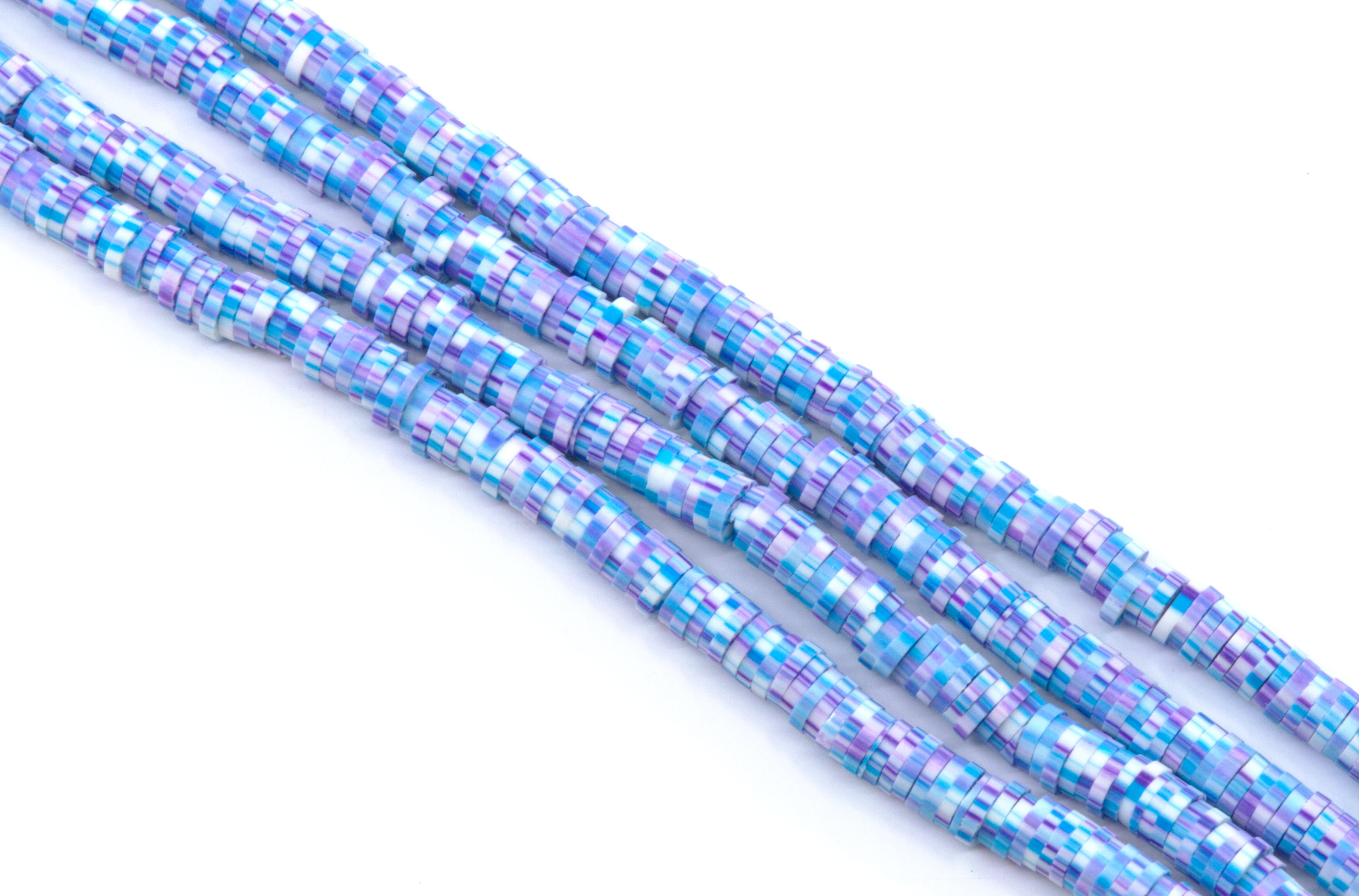 multiple strands of blue and purple polymer clay disc beads arranged diagonally on a plain white background.