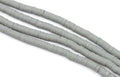 multiple strands of gray polymer clay disc beds  arranged in diagonal strands on a white background.
