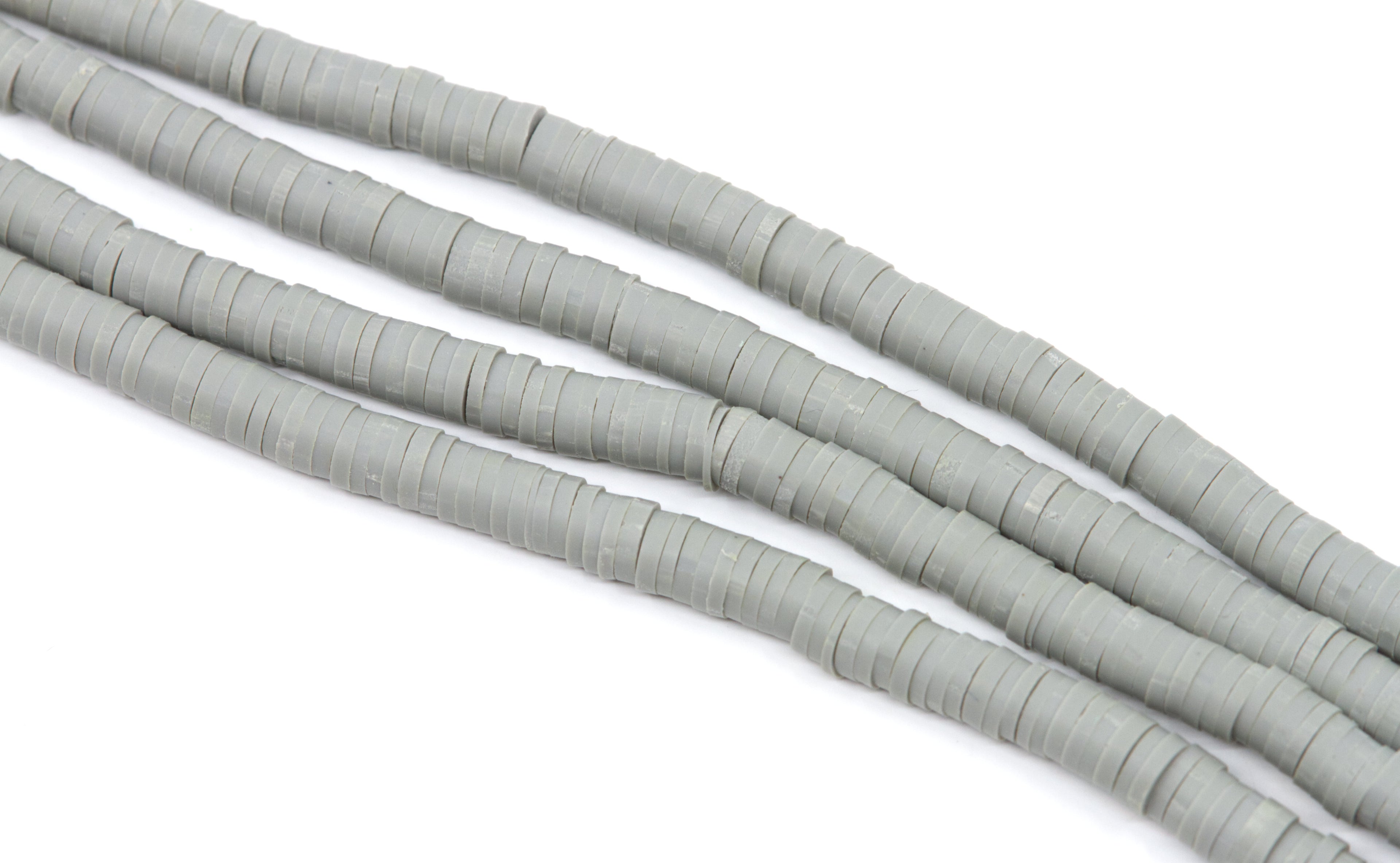 multiple strands of gray polymer clay disc beds  arranged in diagonal strands on a white background.