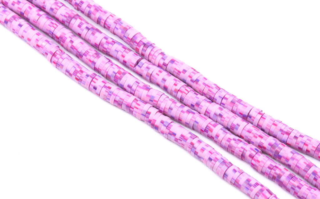 Several strands of pink and purple polymer clay disc beads, arranged diagonally on a plain white background.