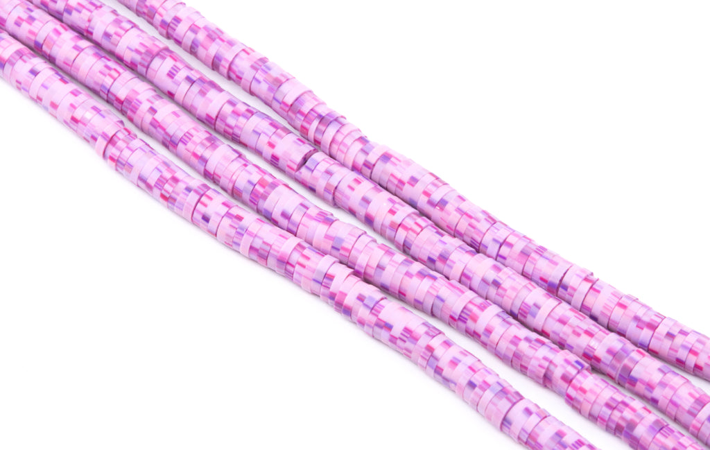 Several strands of pink and purple polymer clay disc beads, arranged diagonally on a plain white background.