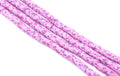 Several strands of pink and purple polymer clay disc beads, arranged diagonally on a plain white background.