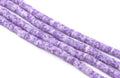 Purple and white polymer clay beads arranged in diagonal strands on a plain white background.