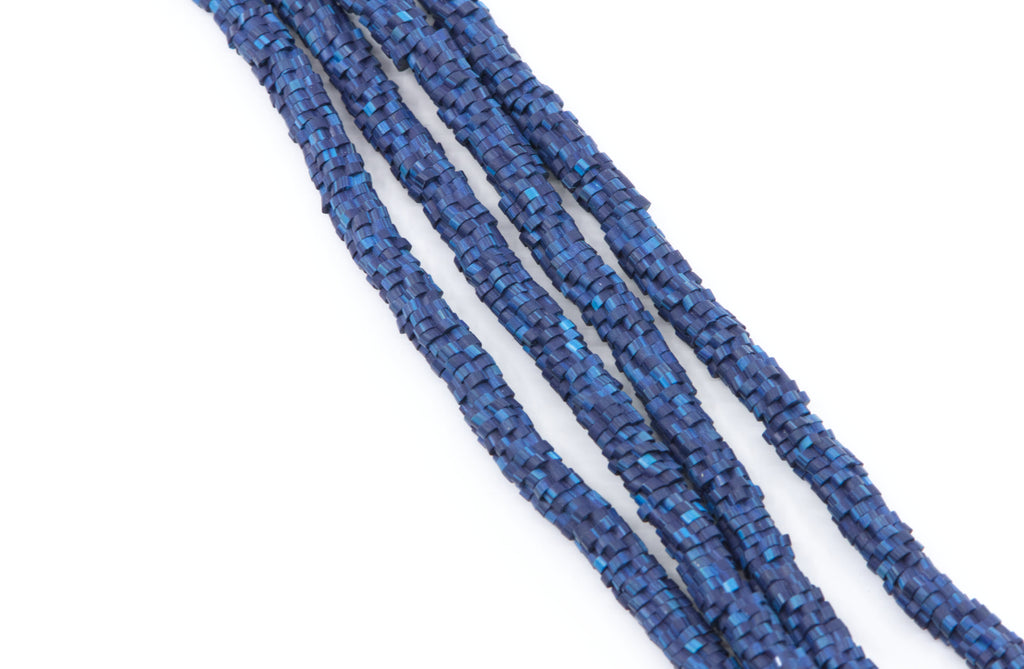 A close-up of several strands of blue polymer clay flower disc beads arranged diagonally on a plain white background.