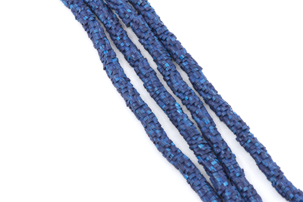 A close-up of several strands of blue polymer clay flower disc beads arranged diagonally on a plain white background.