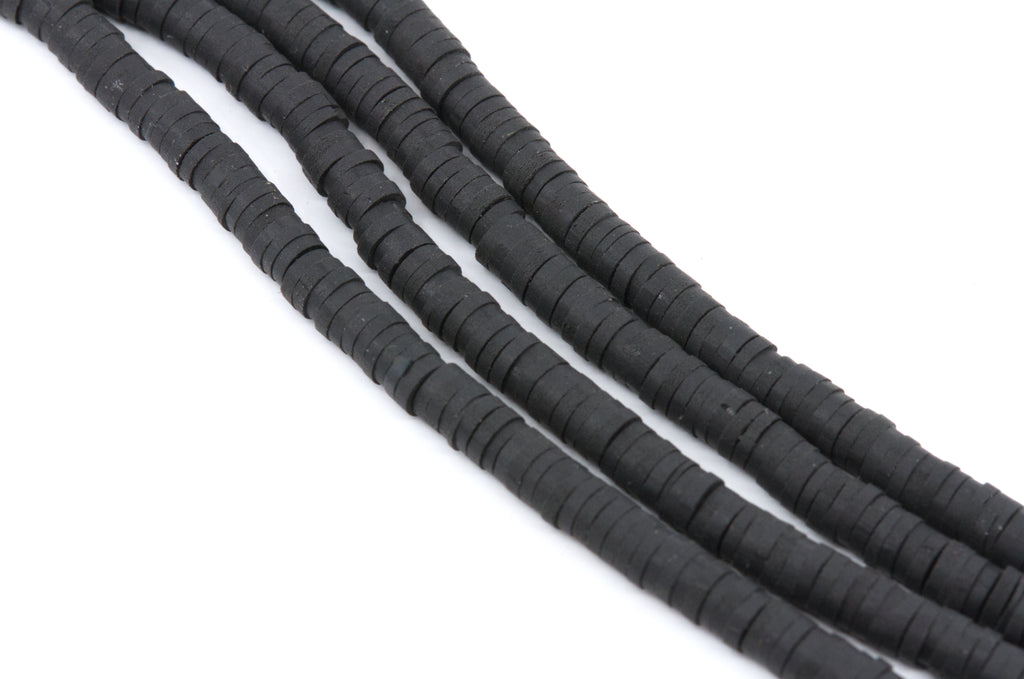 multiple strands of black polymer clay disc beads arranged in diagonal strands on a plain white background.