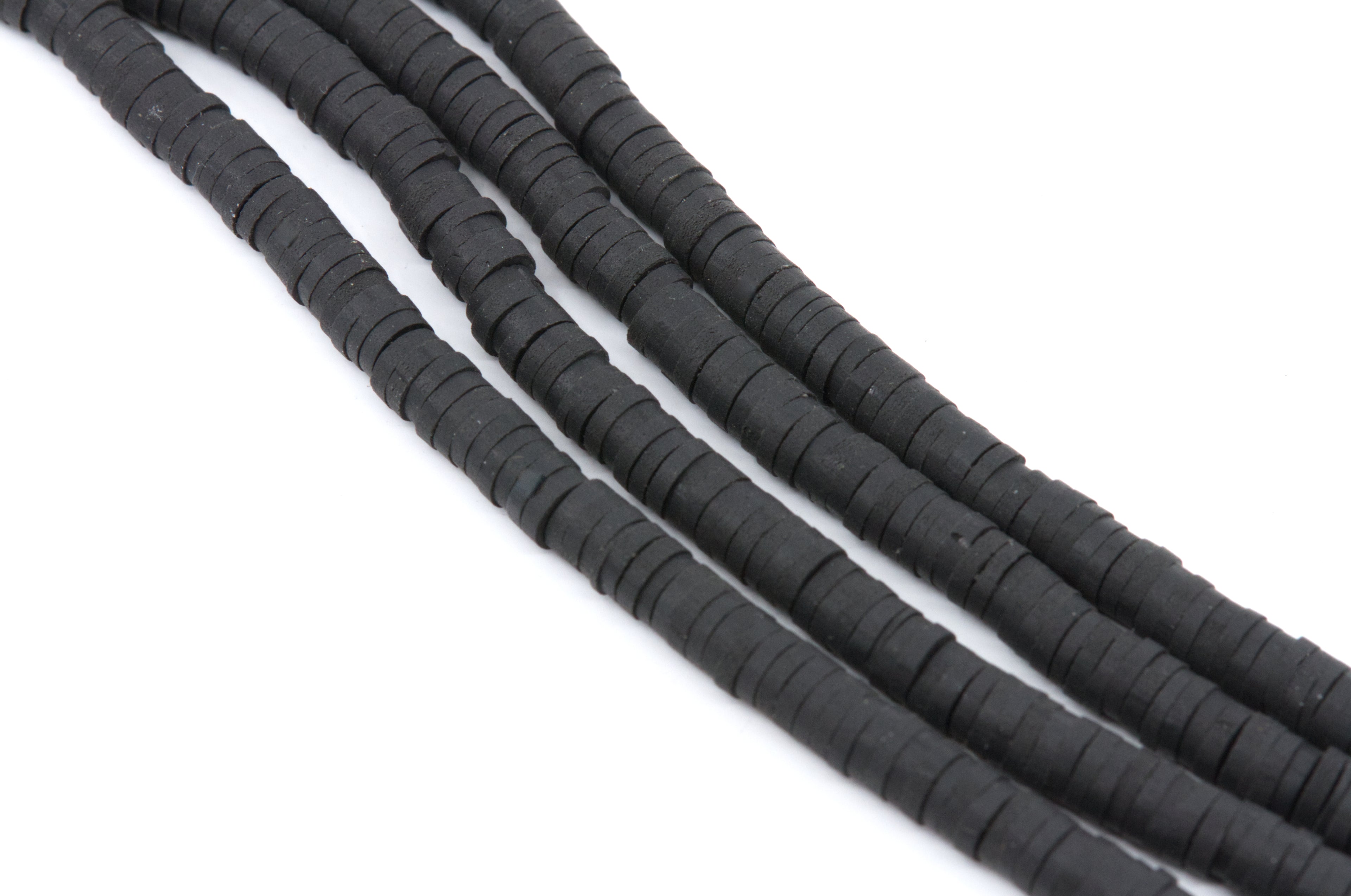 multiple strands of black polymer clay disc beads arranged in diagonal strands on a plain white background.
