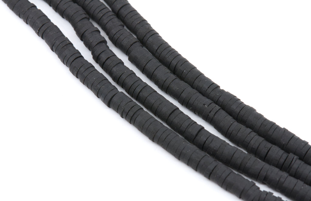 multiple strands of black polymer clay disc beads arranged in diagonal strands on a plain white background.