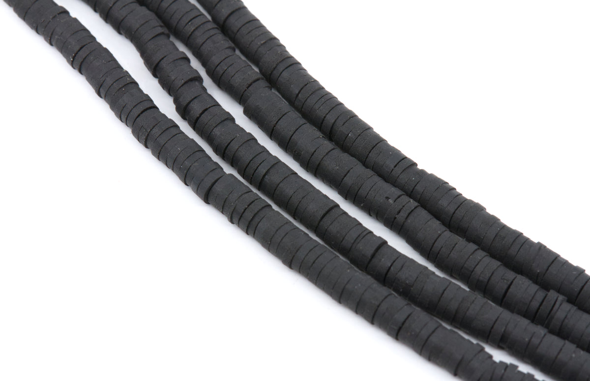 multiple strands of black polymer clay disc beads arranged in diagonal strands on a plain white background.