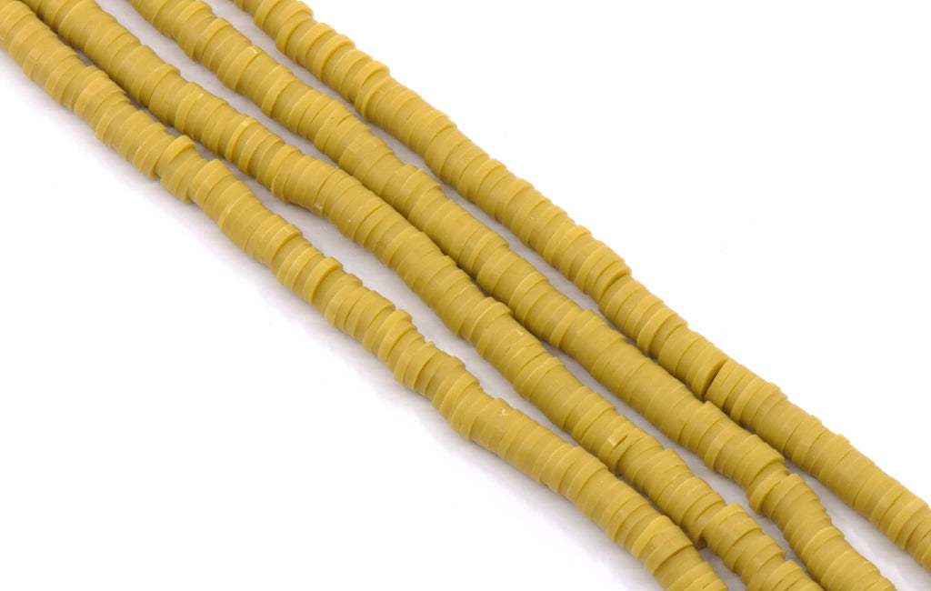multiple strands of mustard yellow polymer clay disc beads arranged diagonally on a plain white background.