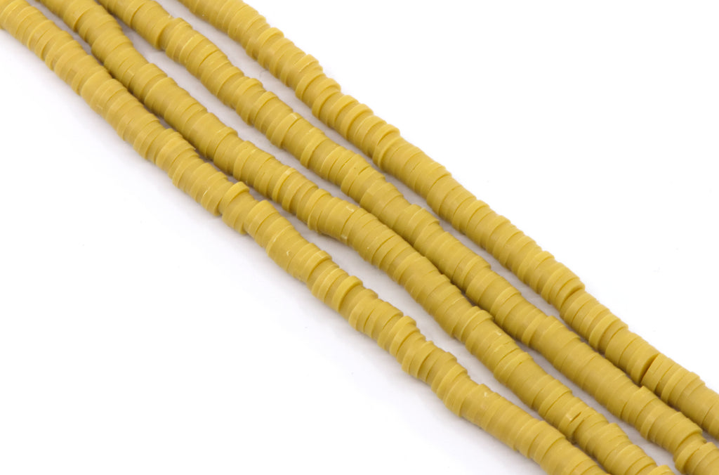 multiple strands of mustard yellow polymer clay disc beads arranged diagonally on a plain white background.