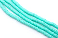 multiple strands of blue polymer clay disc beads arranged in diagonal strands on a clean white background.
