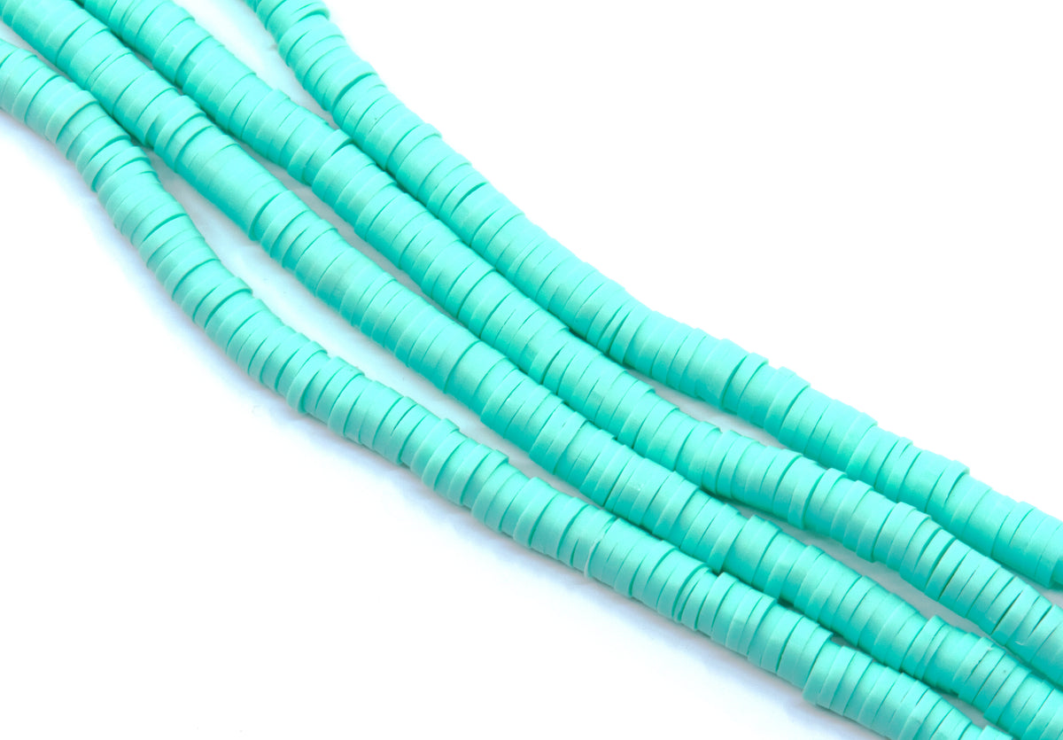 multiple strands of blue polymer clay disc beads arranged in diagonal strands on a clean white background.