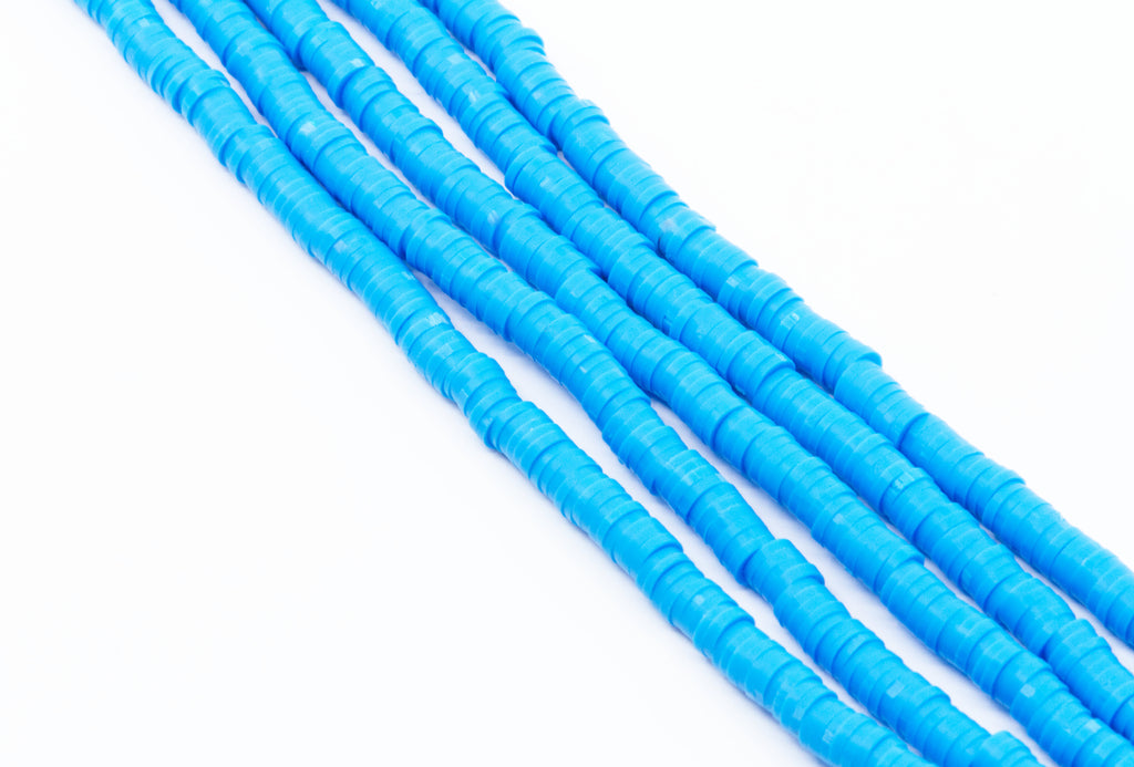 multiple strands of blue polymer clay disc beads arranged diagonally on a plain white background.