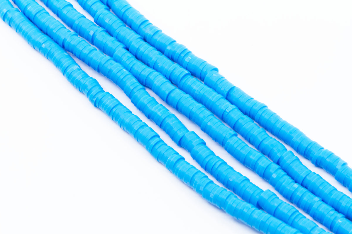 multiple strands of blue polymer clay disc beads arranged diagonally on a plain white background.