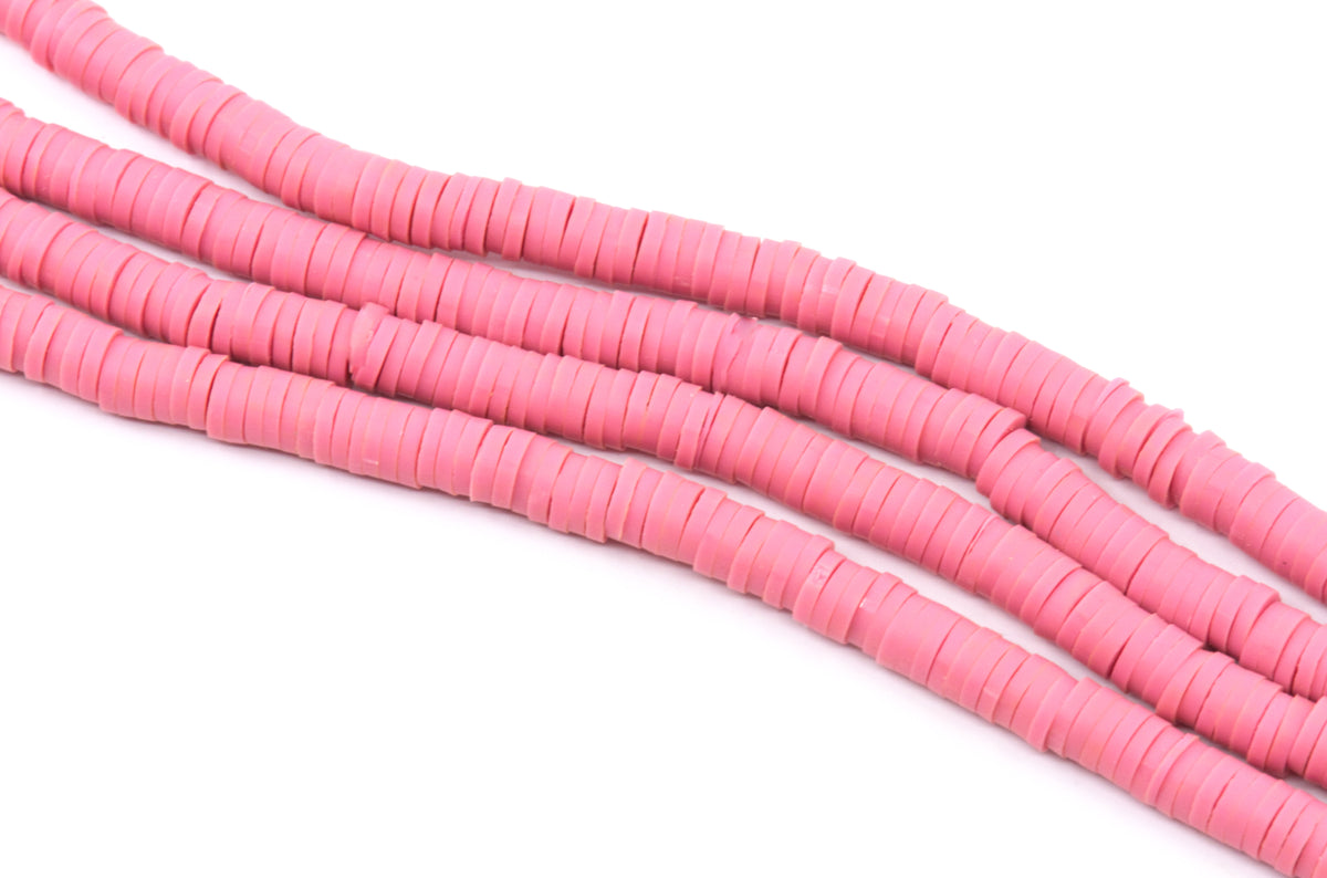 several strand of pink polymer clay disc beads shown diagonally  on a plain white background.