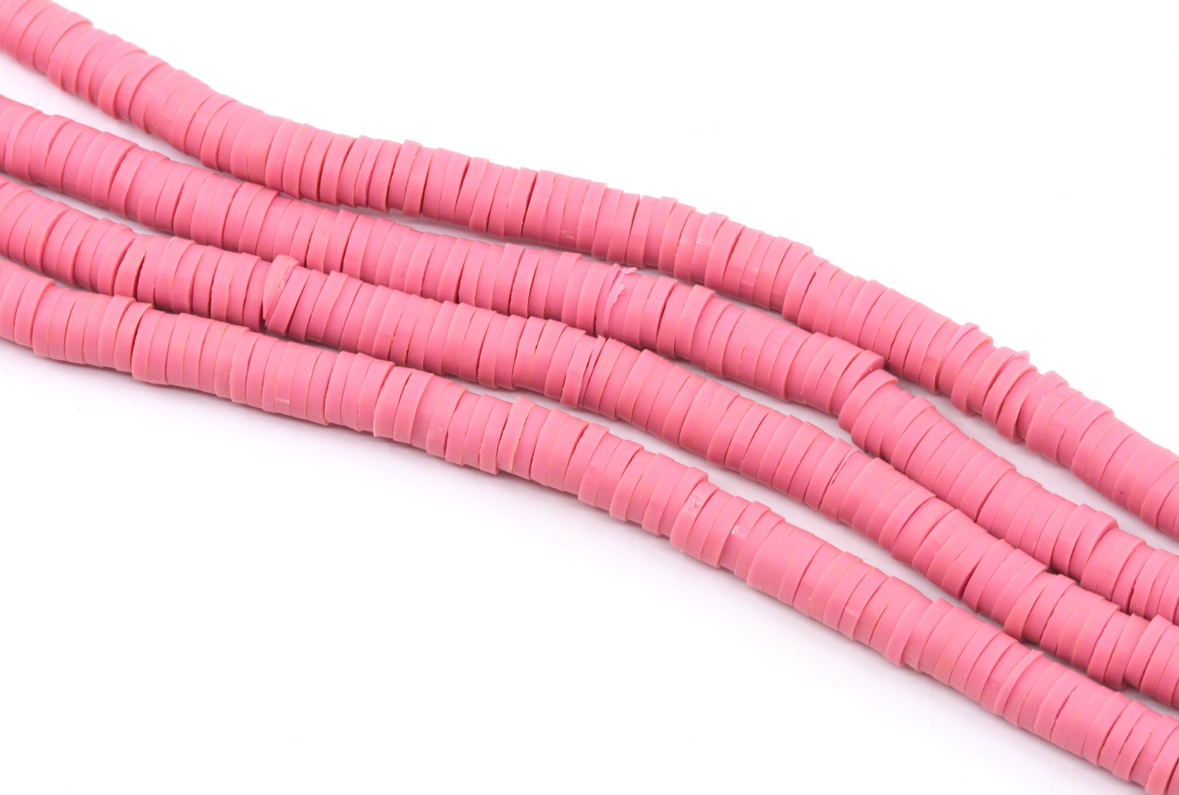 several strand of pink polymer clay disc beads shown diagonally  on a plain white background.